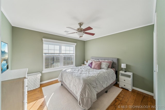 bedroom with ornamental molding, wood finished floors, visible vents, and baseboards