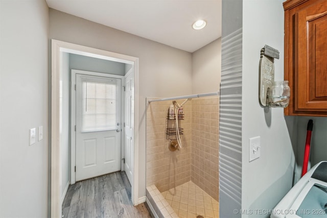 full bathroom with wood finished floors, a shower stall, and washer / dryer