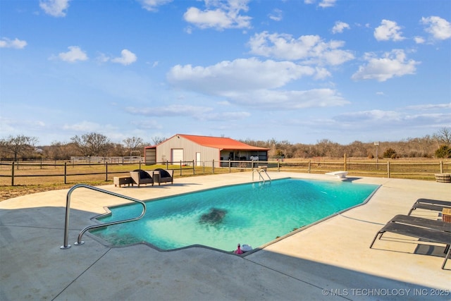 view of pool with a fenced in pool, an outbuilding, a patio area, fence, and a rural view