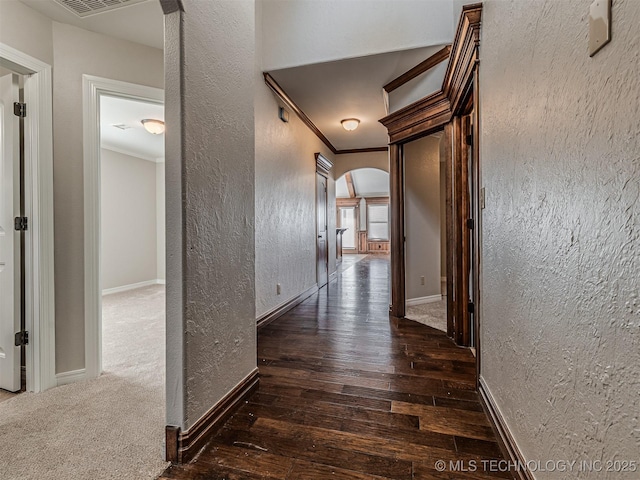 hallway featuring arched walkways, hardwood / wood-style flooring, crown molding, and a textured wall