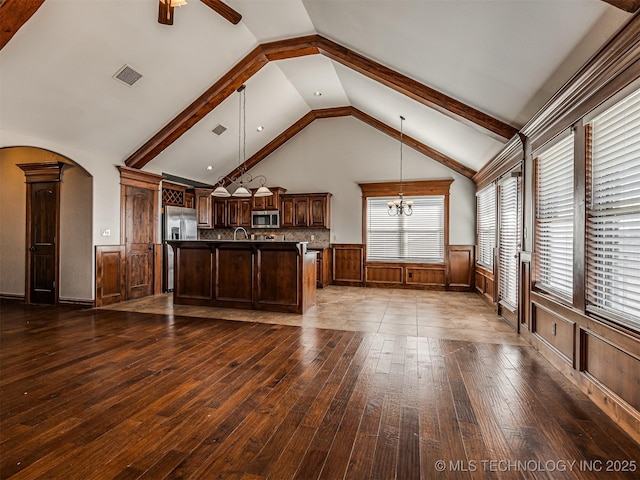 kitchen with a wainscoted wall, visible vents, dark wood-style flooring, arched walkways, and appliances with stainless steel finishes