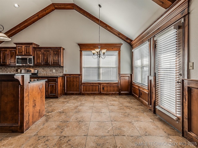 kitchen featuring a wainscoted wall, dark countertops, appliances with stainless steel finishes, and a notable chandelier