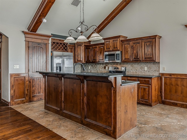 kitchen with dark countertops, visible vents, beamed ceiling, arched walkways, and stainless steel appliances