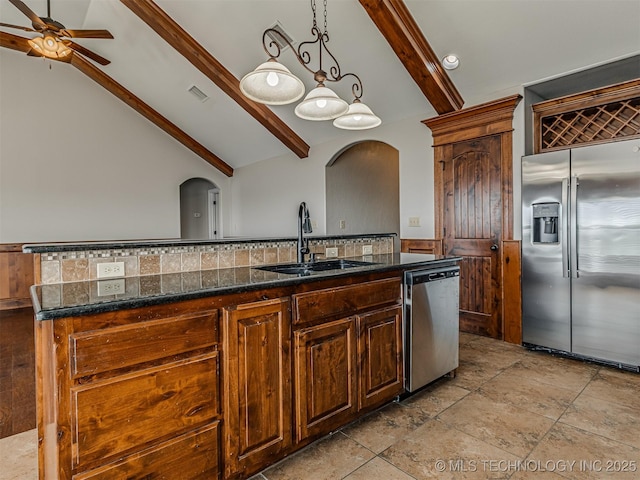 kitchen featuring visible vents, a center island with sink, a sink, stainless steel appliances, and arched walkways