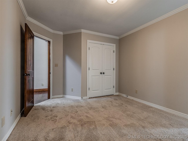 unfurnished bedroom featuring a closet, carpet flooring, crown molding, and baseboards