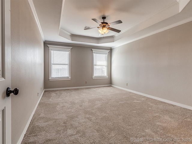 carpeted empty room featuring a raised ceiling, ornamental molding, baseboards, and ceiling fan