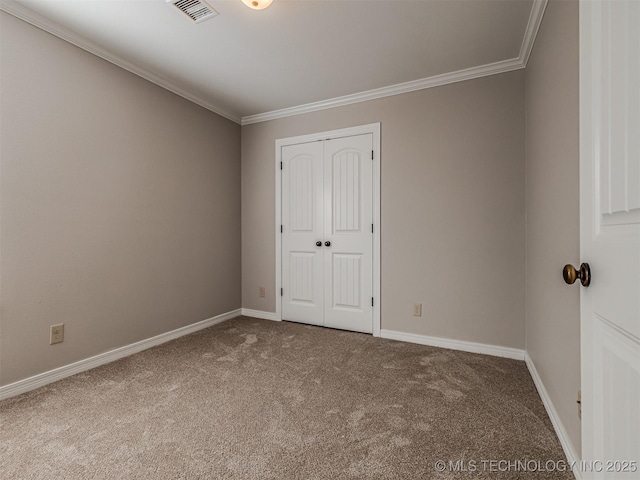 unfurnished bedroom featuring baseboards, visible vents, carpet floors, and ornamental molding