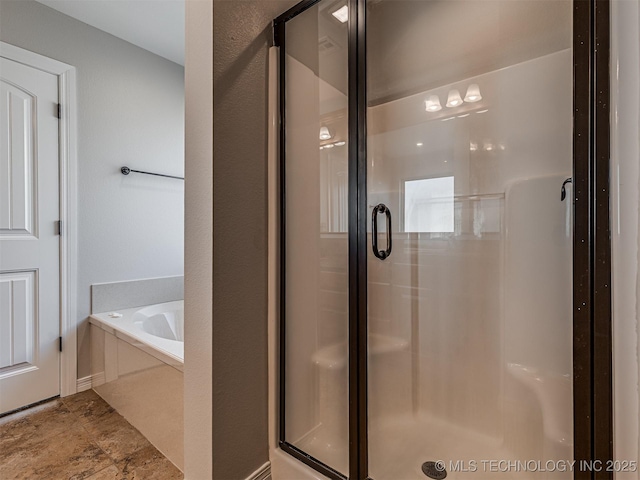 bathroom with a shower stall, a bath, and a textured wall