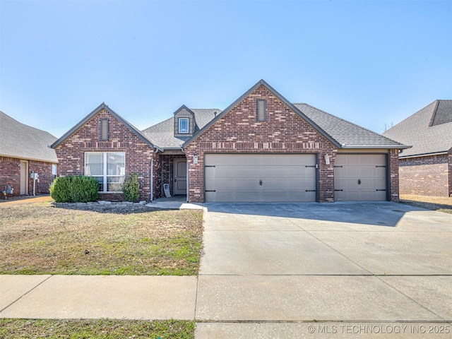 traditional home with a front lawn, driveway, roof with shingles, an attached garage, and brick siding