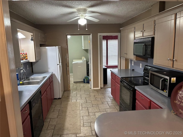 kitchen featuring washing machine and clothes dryer, stone finish flooring, a sink, a textured ceiling, and black appliances