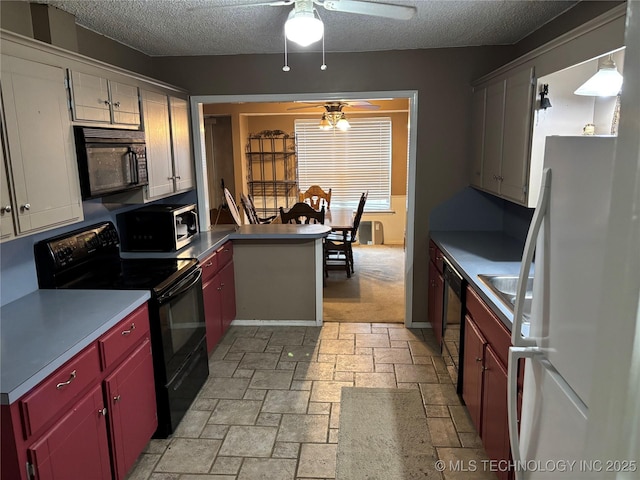 kitchen with a textured ceiling, ceiling fan, a peninsula, black appliances, and stone finish floor