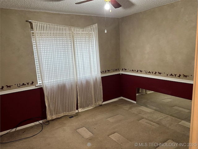 spare room featuring ceiling fan, carpet floors, a textured ceiling, and visible vents