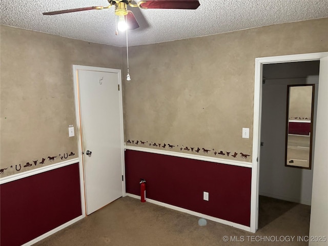 spare room featuring ceiling fan, a textured ceiling, carpet, and baseboards