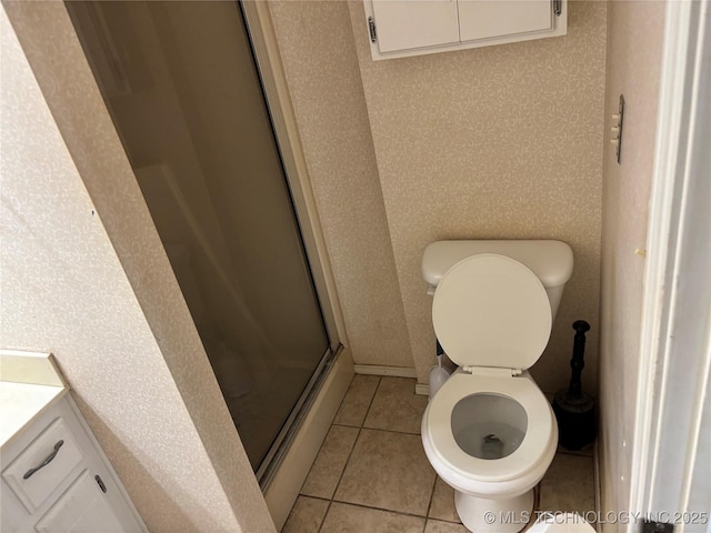 bathroom with a stall shower, vanity, toilet, and tile patterned floors