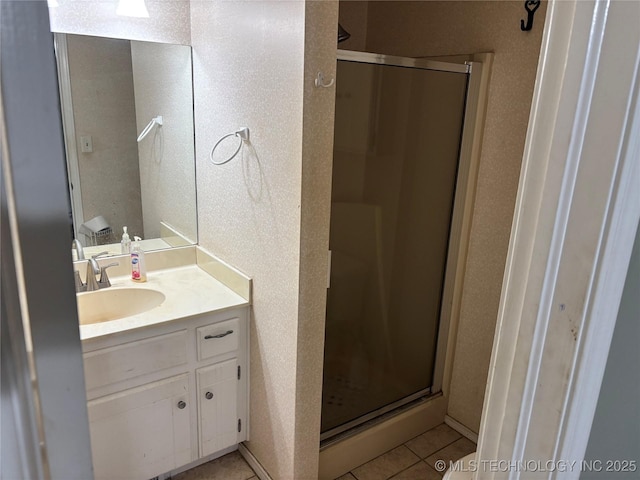 bathroom with tile patterned flooring, a shower stall, and vanity