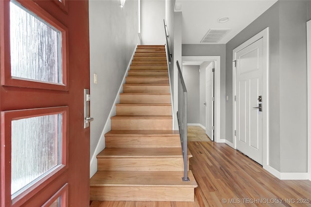 stairway featuring visible vents, baseboards, and wood finished floors