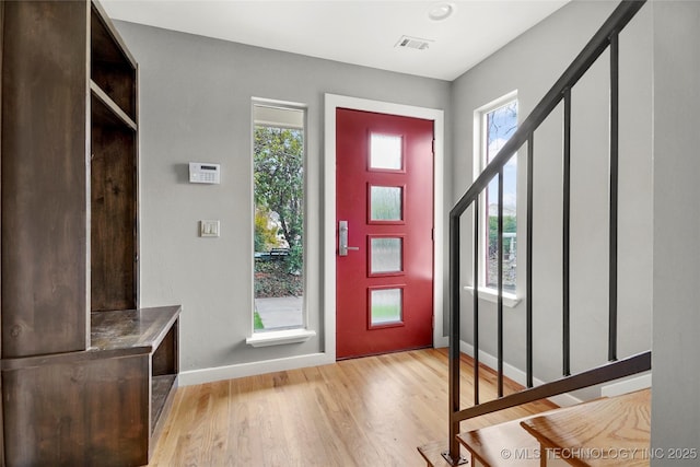 foyer entrance featuring stairway, baseboards, visible vents, and light wood finished floors