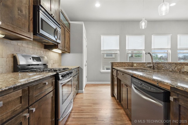 kitchen with appliances with stainless steel finishes, stone counters, a sink, and tasteful backsplash