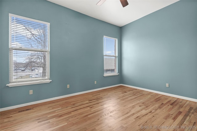 unfurnished room featuring ceiling fan, wood finished floors, visible vents, and baseboards