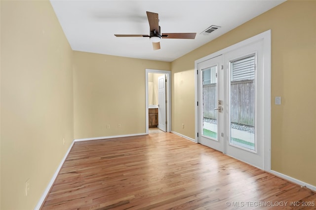 empty room with light wood finished floors, baseboards, visible vents, and a ceiling fan