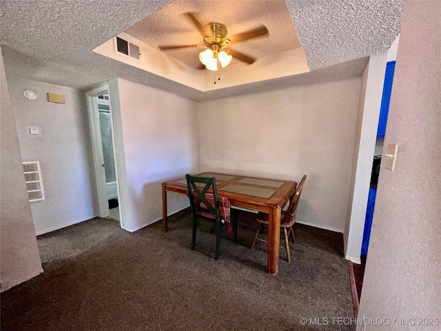 dining space with carpet, a raised ceiling, visible vents, and a textured ceiling