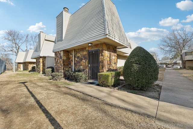 view of front of house featuring stone siding and a chimney