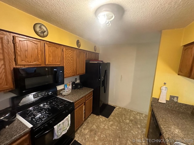 kitchen featuring a textured ceiling, black appliances, brown cabinetry, and dark countertops