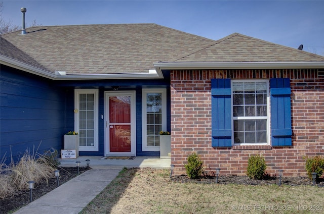 view of front of home with brick siding and roof with shingles