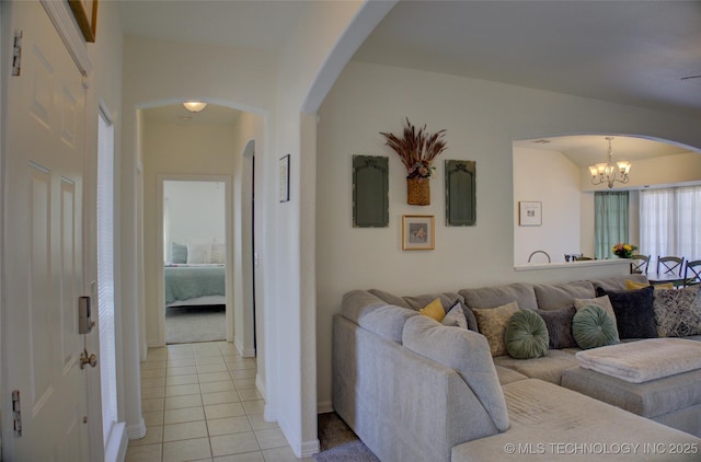 living room featuring arched walkways, a notable chandelier, and light tile patterned floors