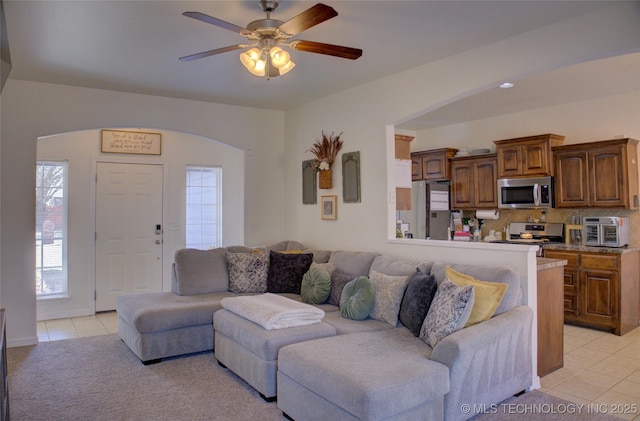 living room featuring light tile patterned floors, ceiling fan, and arched walkways