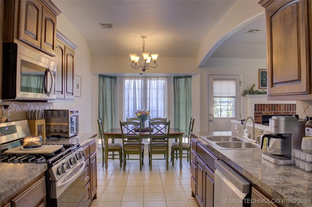 kitchen featuring tasteful backsplash, appliances with stainless steel finishes, a chandelier, and a sink