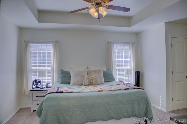 bedroom featuring a tray ceiling, light colored carpet, and baseboards