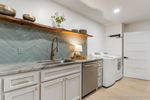 laundry room featuring light wood finished floors, washing machine and clothes dryer, recessed lighting, a sink, and laundry area