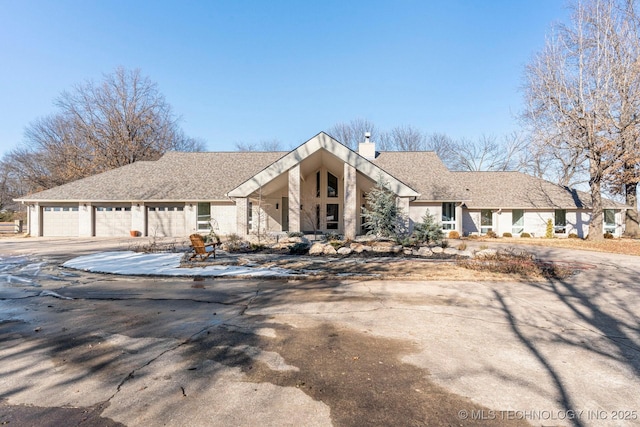 view of front of house with a shingled roof, driveway, and a chimney