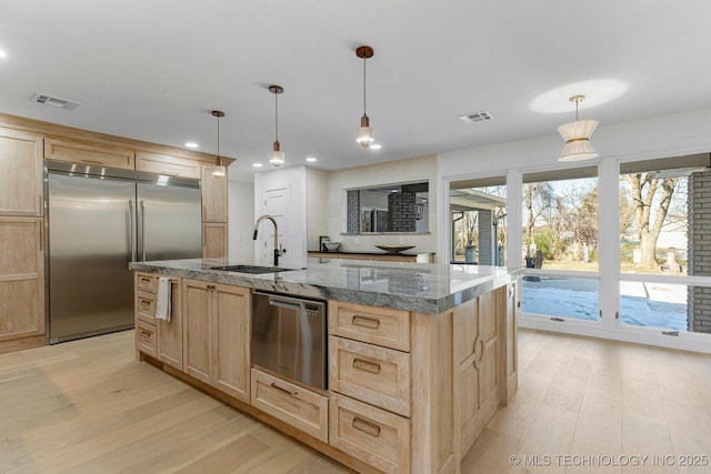 kitchen with stainless steel appliances, light brown cabinets, a sink, and visible vents