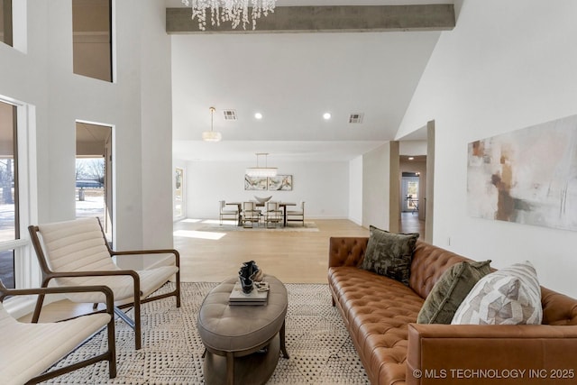 living area with a notable chandelier, visible vents, wood finished floors, and beamed ceiling