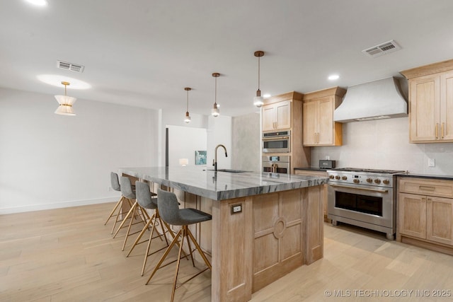 kitchen with custom exhaust hood, stainless steel appliances, visible vents, backsplash, and light brown cabinetry