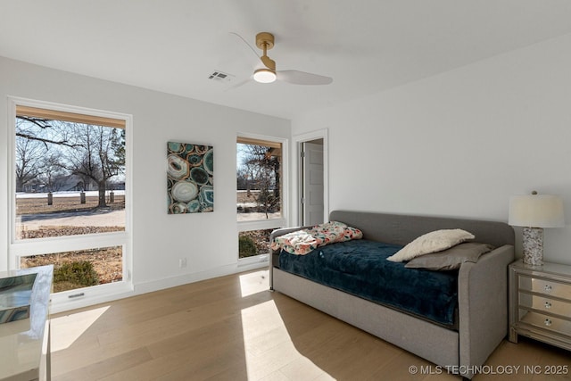 bedroom featuring wood finished floors, visible vents, baseboards, and multiple windows