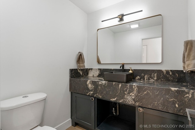 bathroom with baseboards, vanity, and toilet