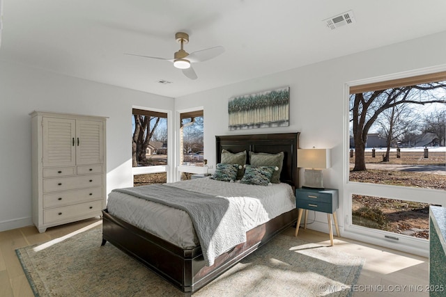 bedroom featuring light wood finished floors, visible vents, and a ceiling fan