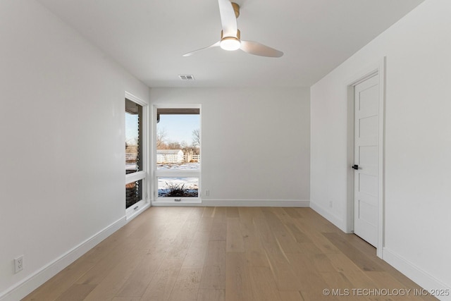 spare room with a ceiling fan, light wood-type flooring, visible vents, and baseboards