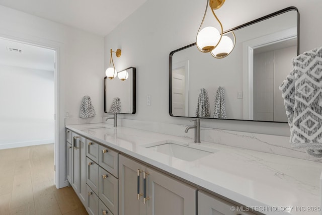 bathroom with double vanity, visible vents, a sink, and wood finished floors