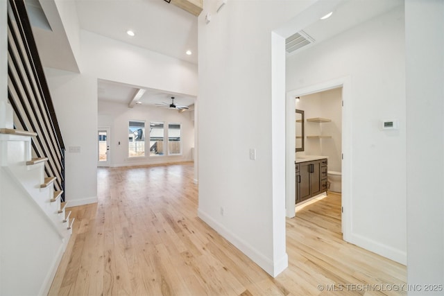 interior space featuring beamed ceiling, light wood-type flooring, visible vents, and baseboards