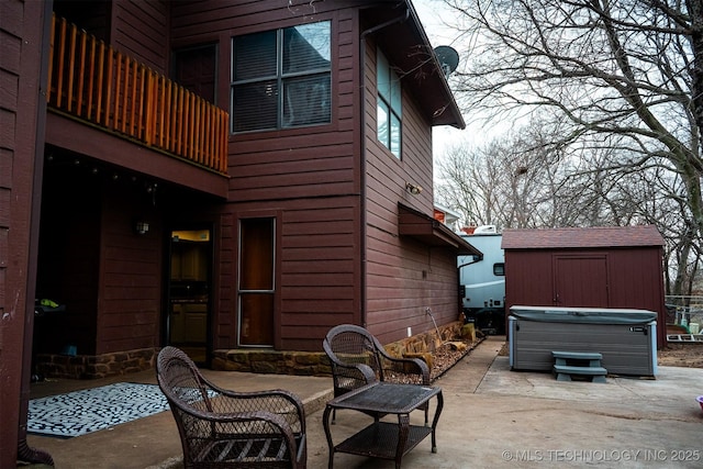 view of patio / terrace with an outbuilding, a hot tub, and a storage shed