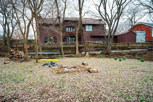 back of house with a trampoline and a fire pit