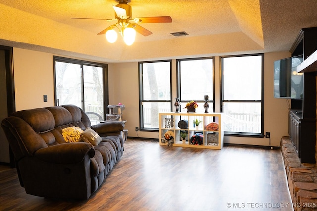 living room with a tray ceiling, plenty of natural light, and wood finished floors