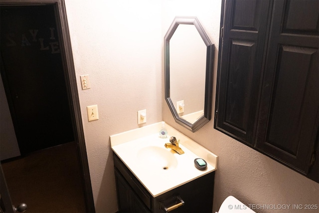 half bathroom with a textured wall and vanity