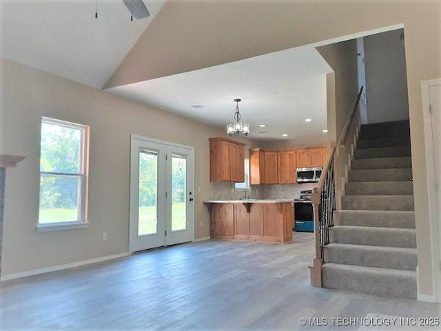 kitchen with tasteful backsplash, open floor plan, a peninsula, stainless steel appliances, and light countertops