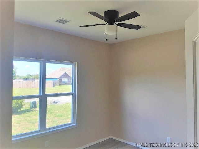 spare room featuring a ceiling fan, light wood-type flooring, visible vents, and baseboards