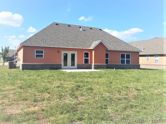 back of house featuring french doors, brick siding, a lawn, and central air condition unit